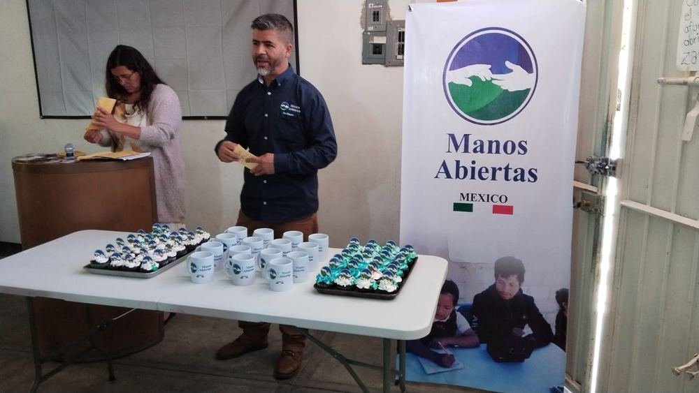Facilitador de Manos Abiertas México durante un evento, junto al banner de la fundación